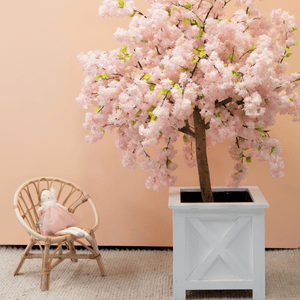 150cm cherry blossom tree in planter box next to next to dolls rattan chair in front of peach wall
